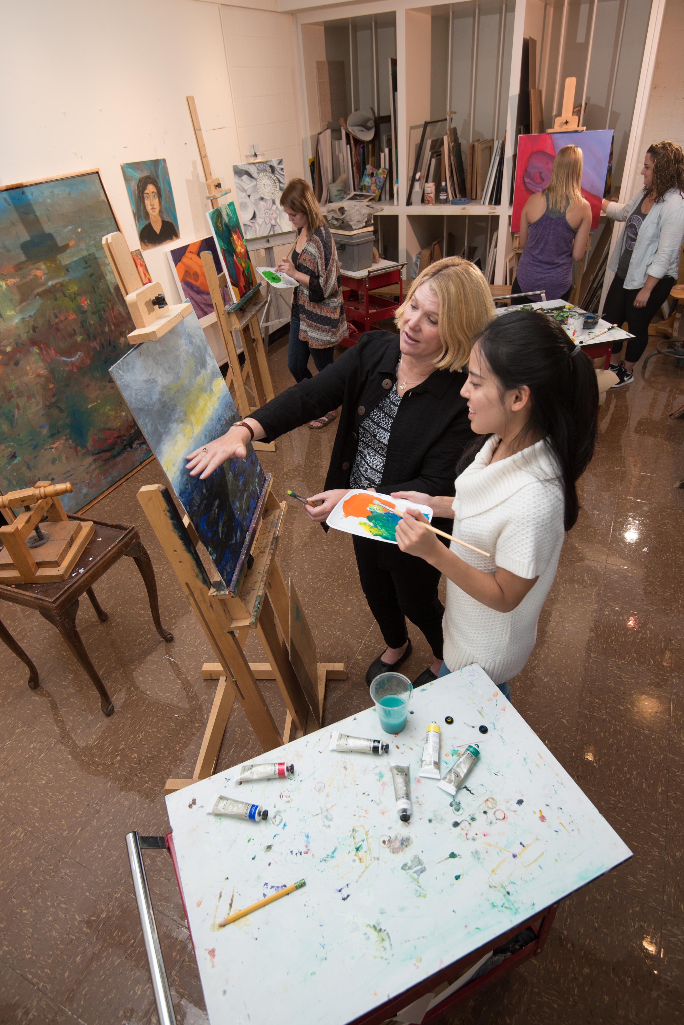 Art student and professor working on a painting project 